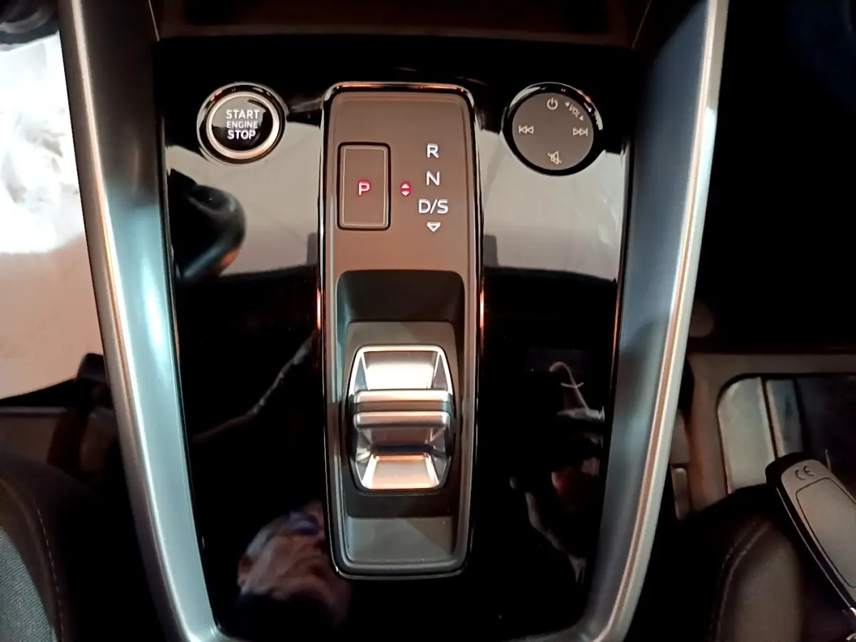 Vue plongeante sur la console centrale noire brillante de l'Audi A3 35 TFSI avec sélecteur de boîte auto et bouton start/stop.