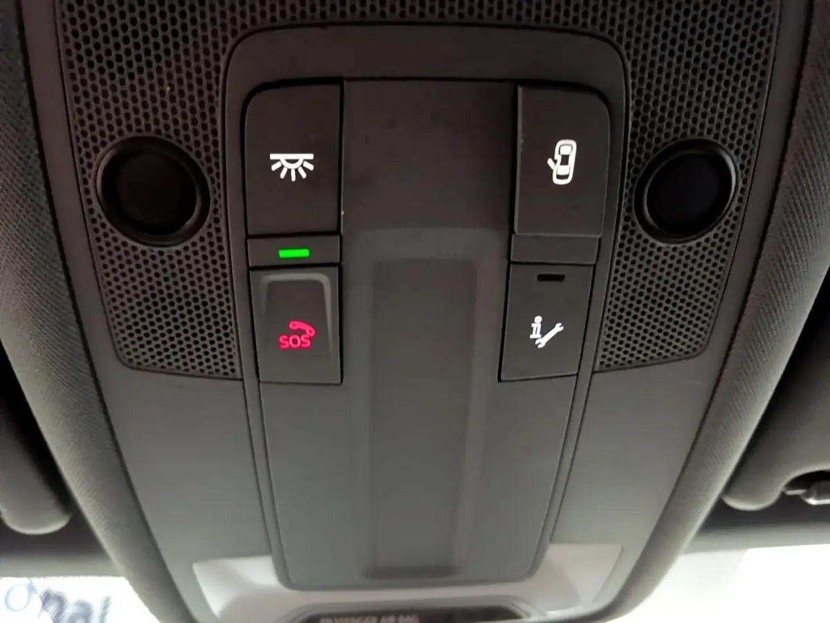 Vue en contre-plongée du panneau de commandes au plafond intérieur gris foncé de l'Audi A3 avec bouton SOS éclairé en rouge.