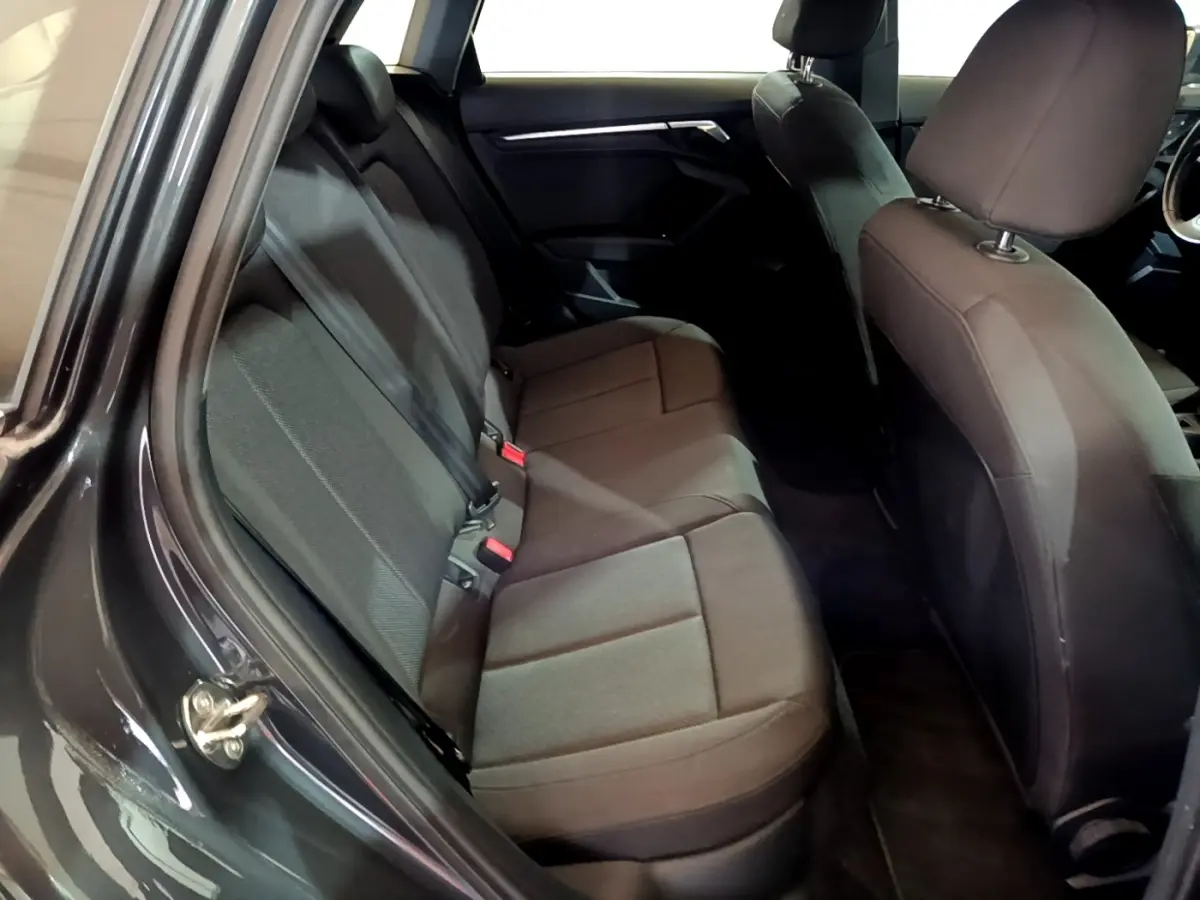 Vue intérieure côté gauche montrant la banquette arrière en tissu gris foncé de l'Audi A3 35 TFSI 2021.