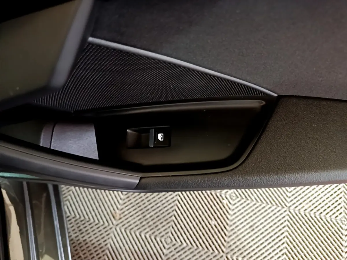 Gros plan sur le bouton de verrouillage des portes côté conducteur de l'Audi A3 gris foncé, intérieur.