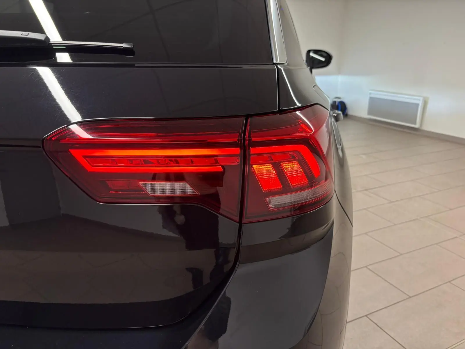 Gros plan sur le feu arrière droit d’un Volkswagen T-Roc noir intense, mettant en valeur ses lignes lumineuses modernes.