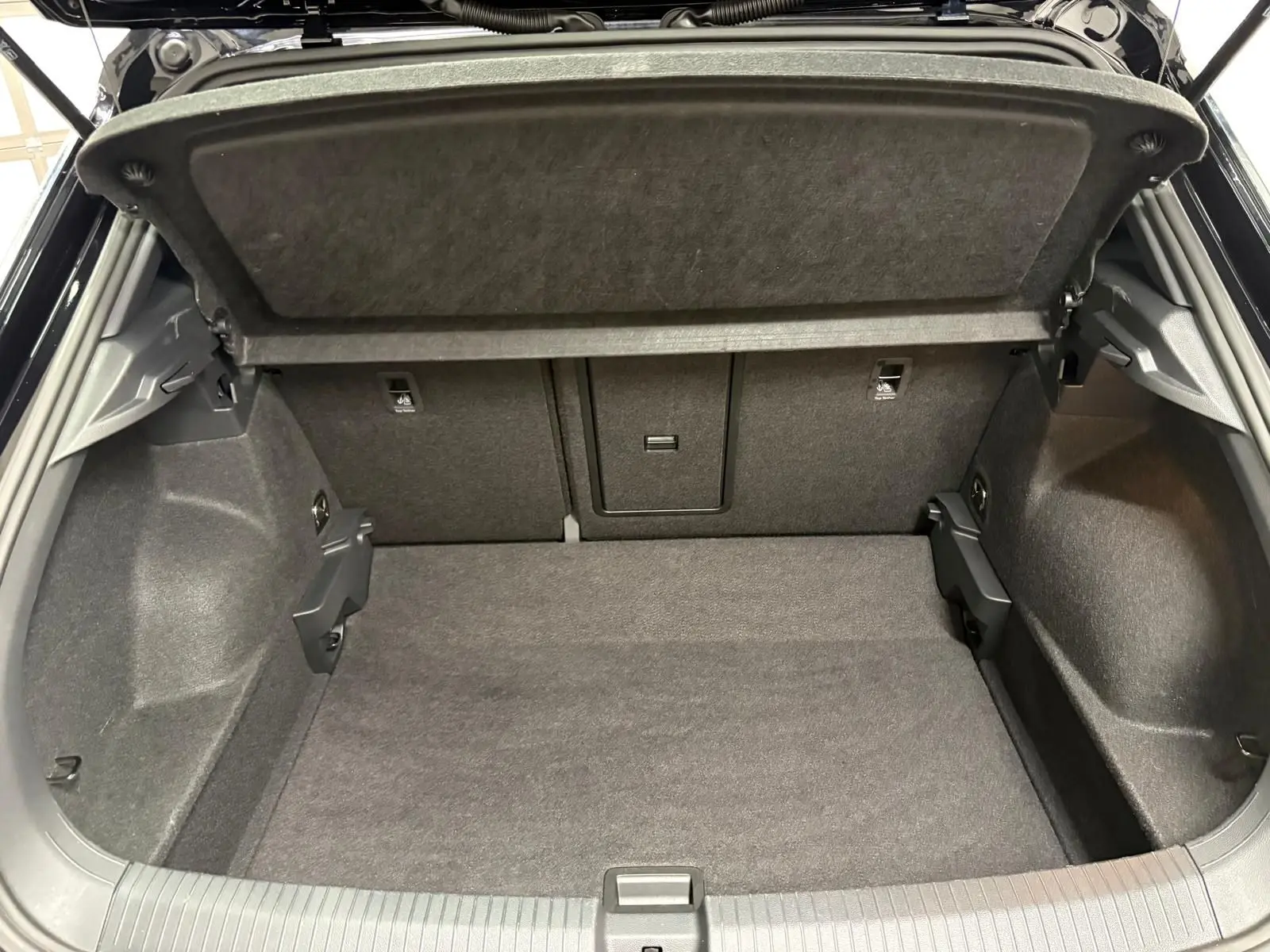 Coffre ouvert du Volkswagen T-Roc noir intense 2025, montrant un espace de chargement propre et spacieux.