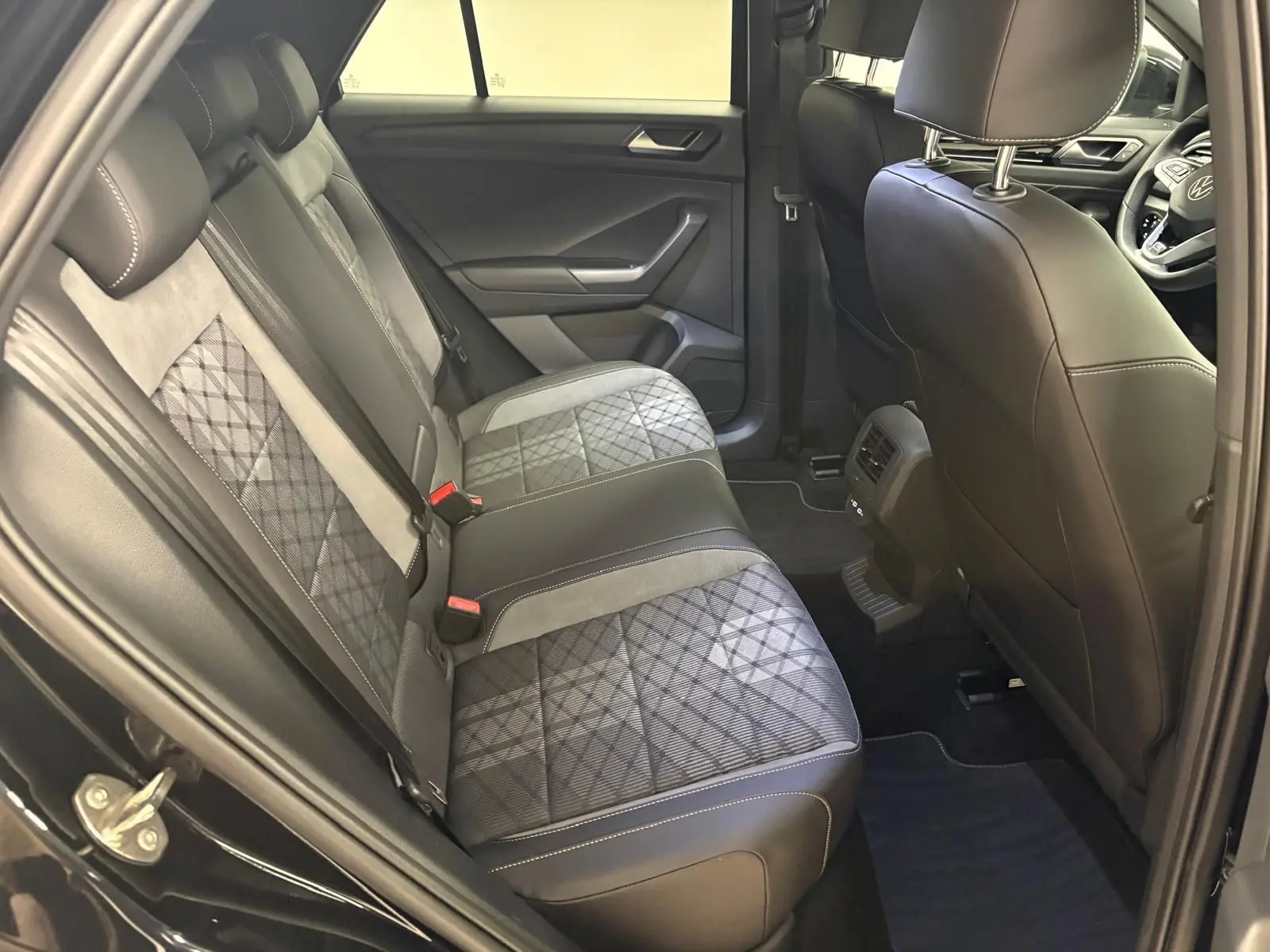 Vue intérieure côté gauche sur les sièges arrière en cuir noir et tissu à motif du Volkswagen T-Roc 2025 noir intense.