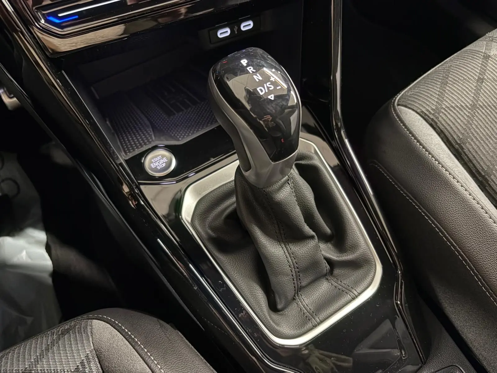 Gros plan sur le levier de vitesse automatique noir brillant du Volkswagen T-Roc 1.5 TSI R-Line, avec bouton start/stop visible.
