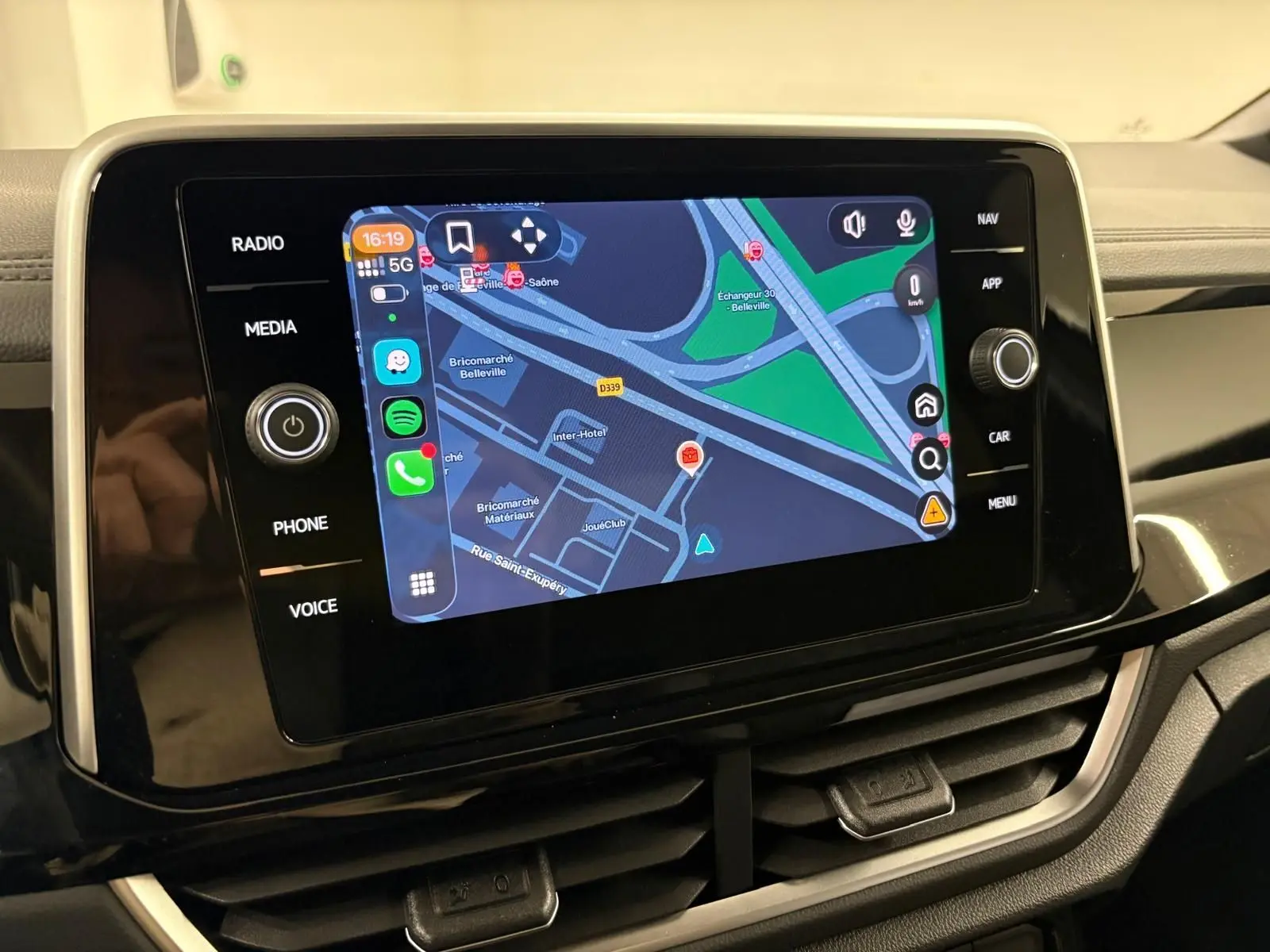 Écran tactile central du Volkswagen T-Roc 2025 affichant la navigation, entouré de commandes noires brillantes.