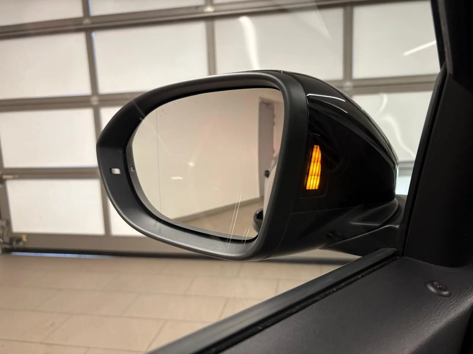 Rétroviseur droit noir intense du Volkswagen T-Roc 2025 avec clignotant orange allumé en intérieur.