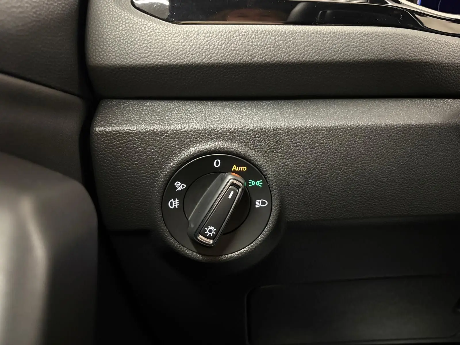 Gros plan sur le bouton de commande des phares du Volkswagen T-Roc 1.5 TSI 150 DSG7 R-Line Edition, intérieur noir.