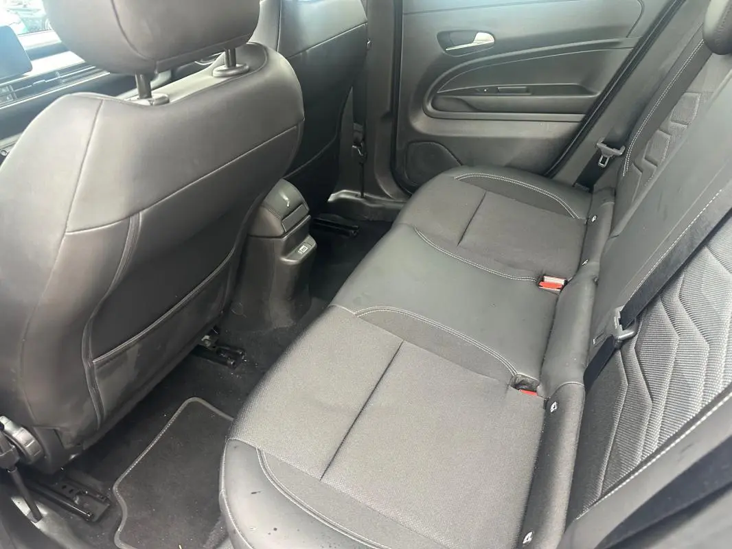 Vue intérieure arrière côté droit du Jeep Avenger 2025, sièges tissu et cuir noirs avec ceinture de sécurité visible.