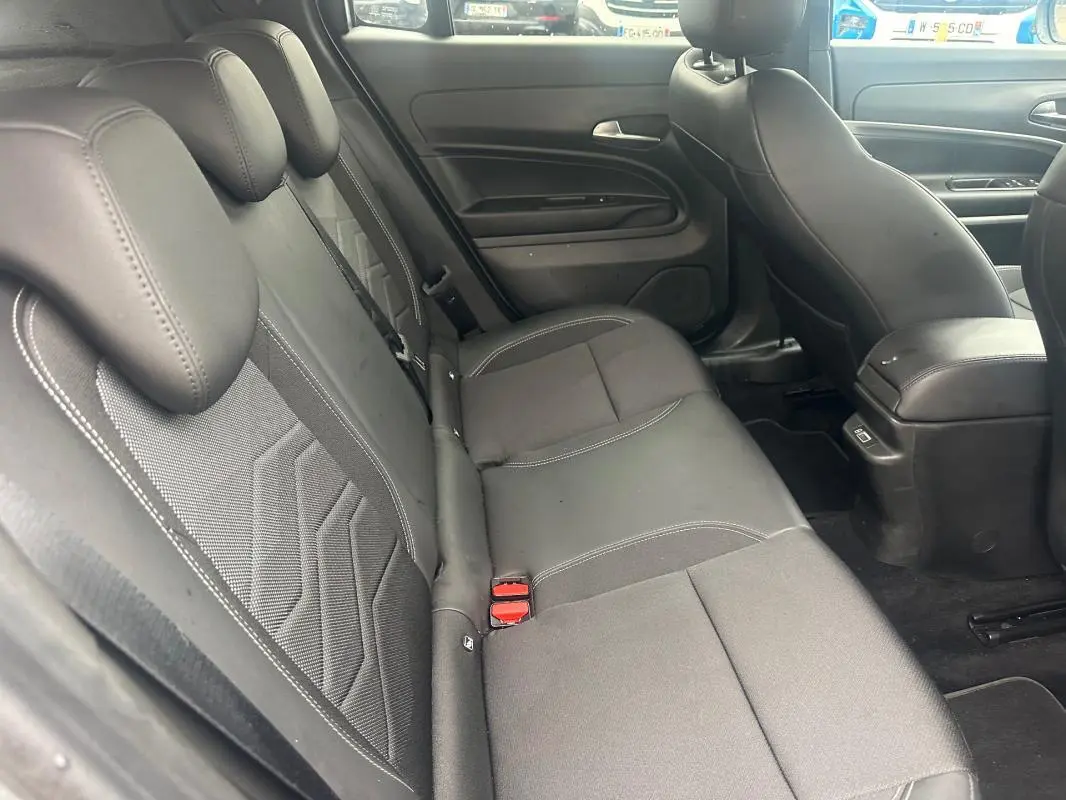 Vue intérieure côté gauche des sièges arrière gris foncé du Jeep Avenger 2025 avec accoudoir central et finitions en tissu.