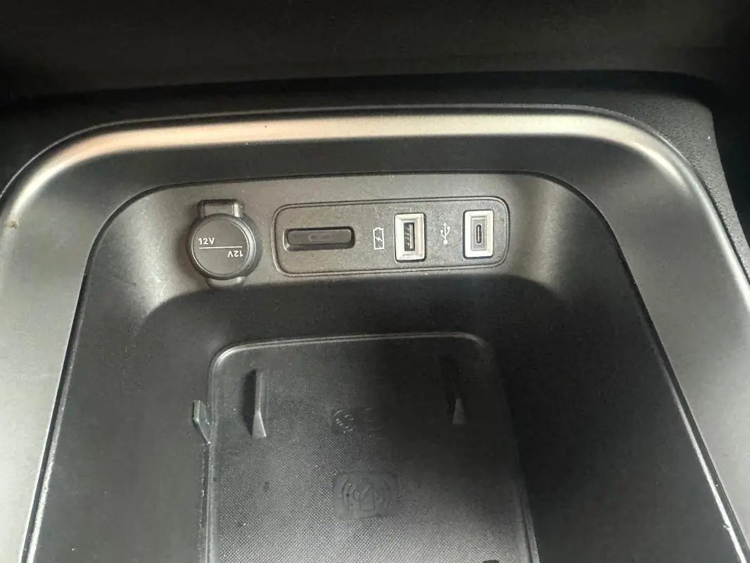 Vue rapprochée de la console centrale du Jeep Avenger 2025, montrant prises USB, prise 12V et zone de recharge sans fil noire.