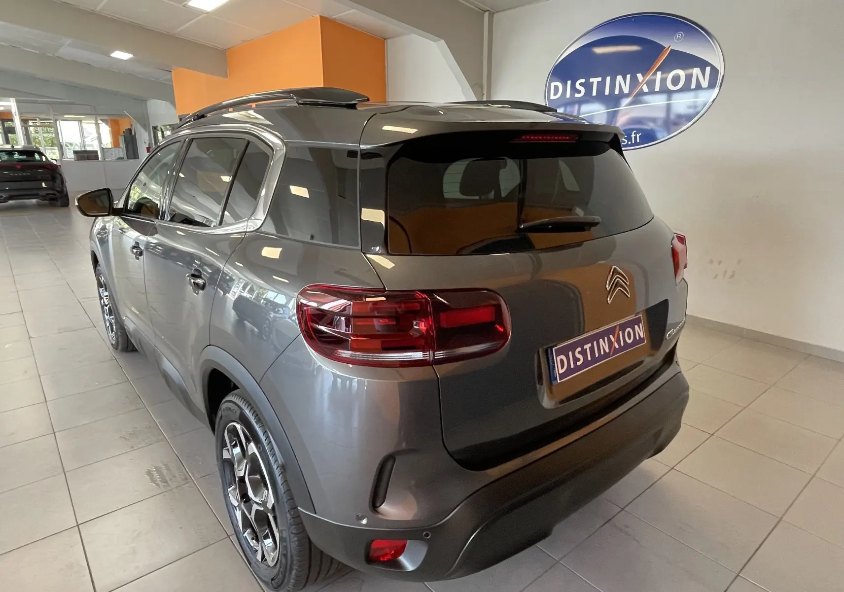 Vue 3/4 arrière gauche du Citroën C5 Aircross gris platinium avec vitres surteintées et jantes alliage 18 pouces biton.