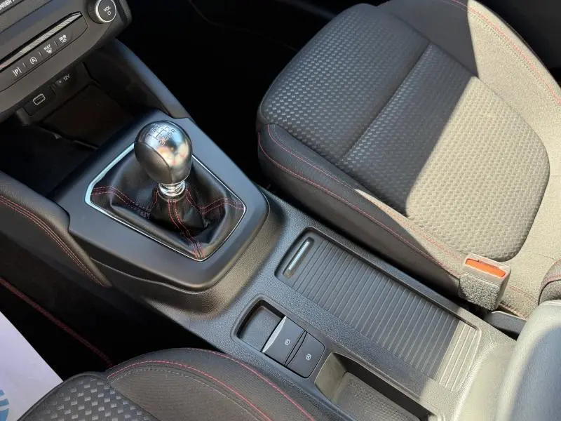 Vue rapprochée de la console centrale et du levier de vitesses manuel de la Ford Focus SW 2023 avec surpiqûres rouges.