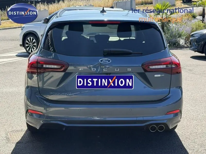 Vue arrière d'une Ford Focus SW 2023 bleu azur métallisé avec double sortie d'échappement et logo ST-Line X visible.
