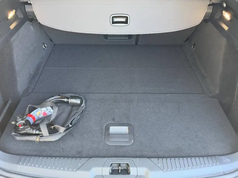Coffre ouvert vu de l'arrière d'une Ford Focus SW 2023 Bleu Azur métallisé avec câble de recharge posé à gauche.
