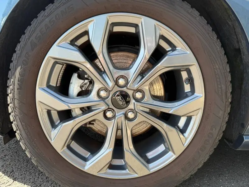 Gros plan sur la jante alliage argentée avec logo Ford, roue avant droite d'une Ford Focus SW Bleu Azur métallisé 2023.