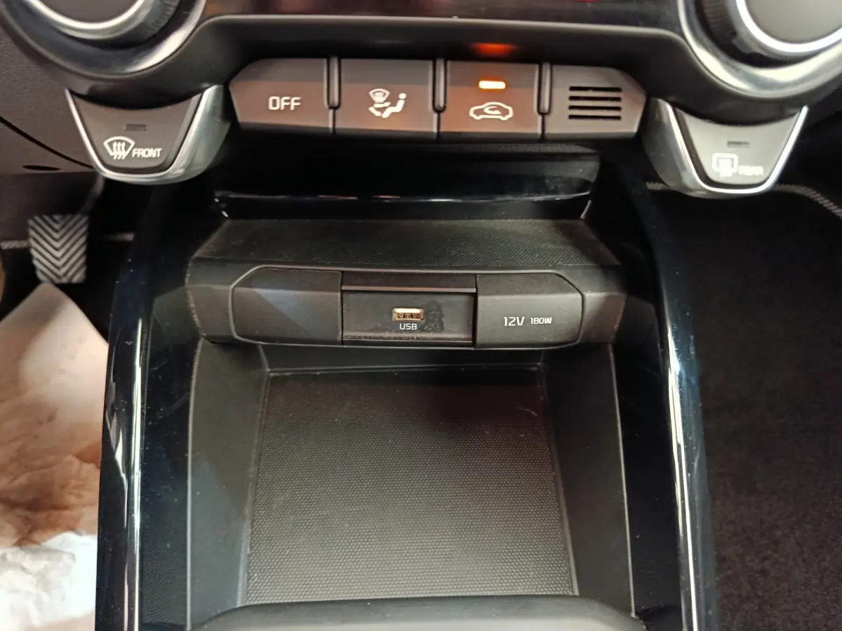 Vue rapprochée du compartiment central noir avec prise USB et port 12V dans l’habitacle d’une KIA Stonic 2023.