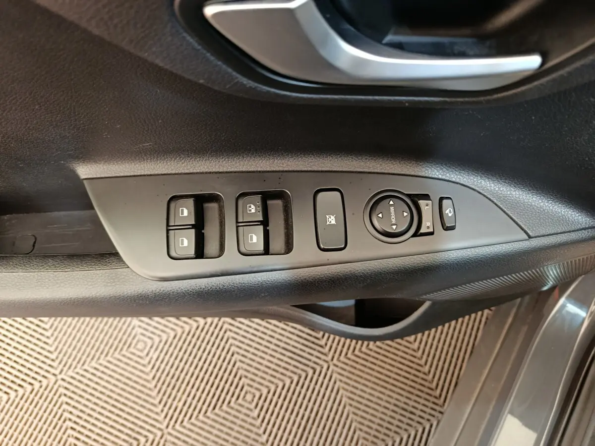 Gros plan sur la commande des vitres et rétroviseurs côté conducteur du KIA Stonic gris foncé 2023.