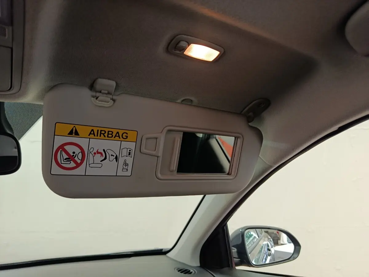 Vue intérieure côté conducteur du pare-soleil déplié avec miroir et avertissement airbag dans un Kia Stonic gris foncé 2023.