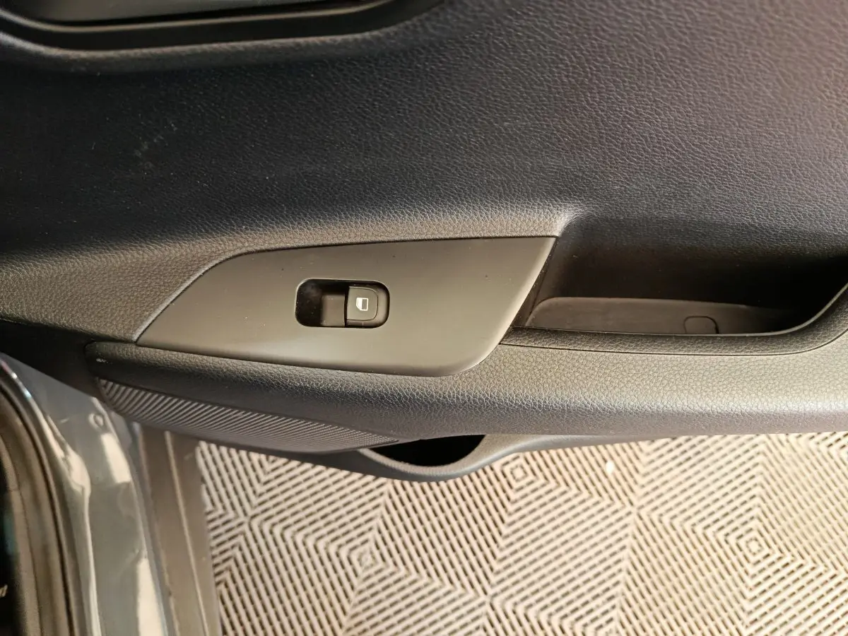 Détail de la porte côté conducteur du Kia Stonic gris foncé 2023 avec bouton de verrouillage centralisé.