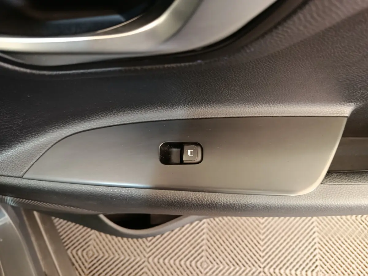 Gros plan sur le bouton de verrouillage des portes côté conducteur dans l'intérieur gris foncé de la KIA Stonic 2023.
