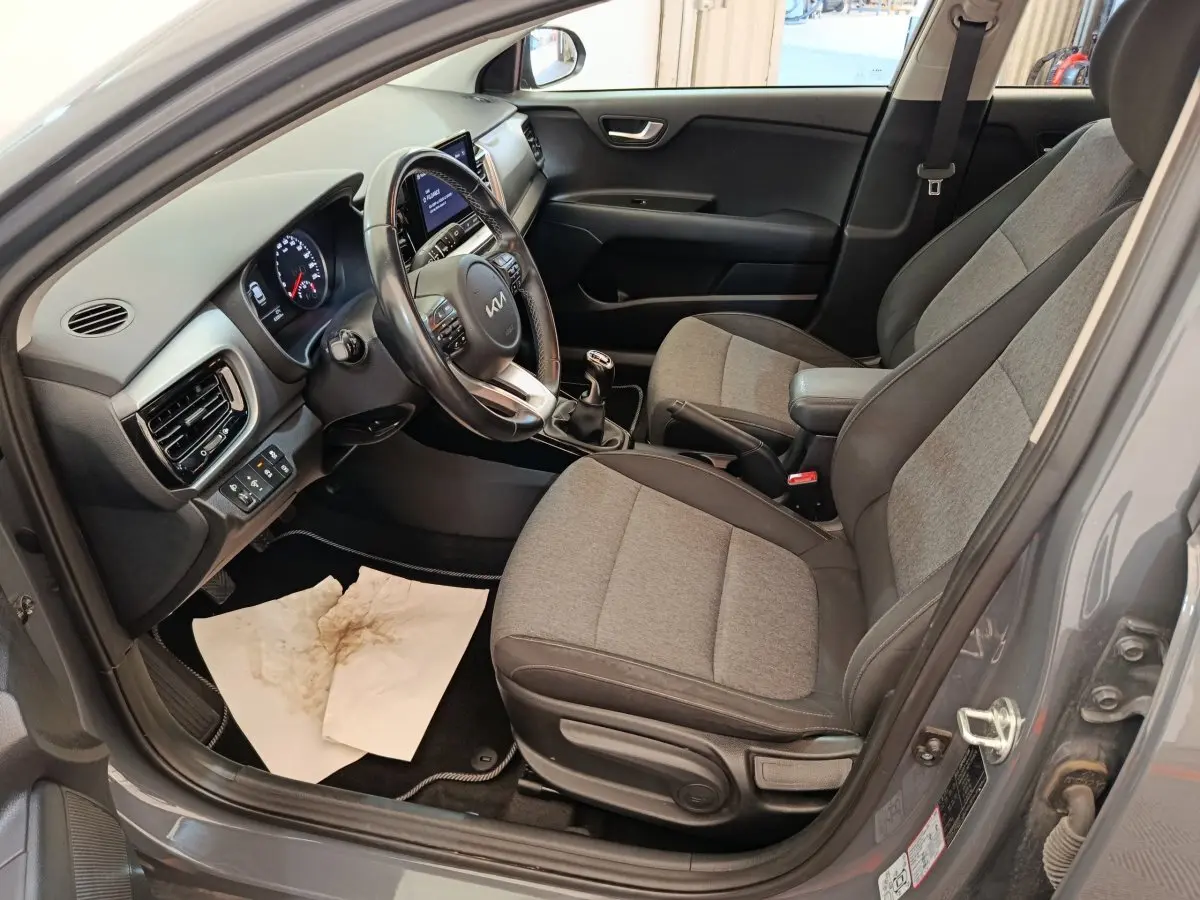 Vue intérieure côté conducteur de la KIA Stonic gris foncé 2023 avec sièges tissu bicolore et volant cuir multifonctions.