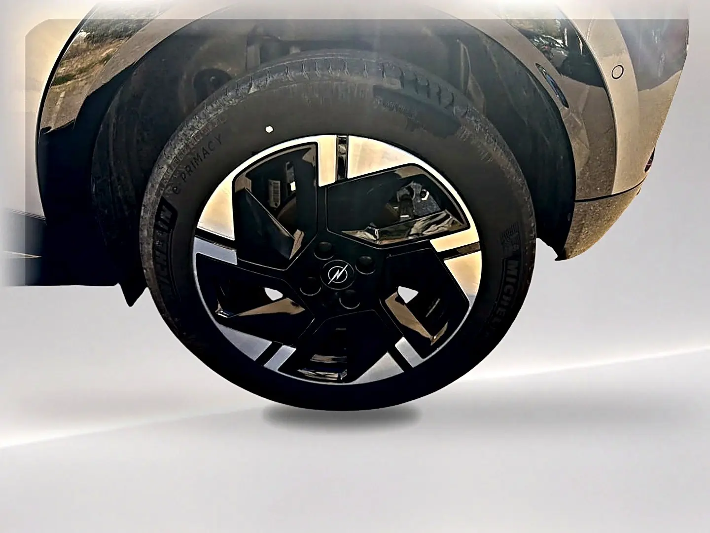 Gros plan sur la roue avant droite avec jante alu noire et grise de l'Opel Mokka Electric gris 2025.