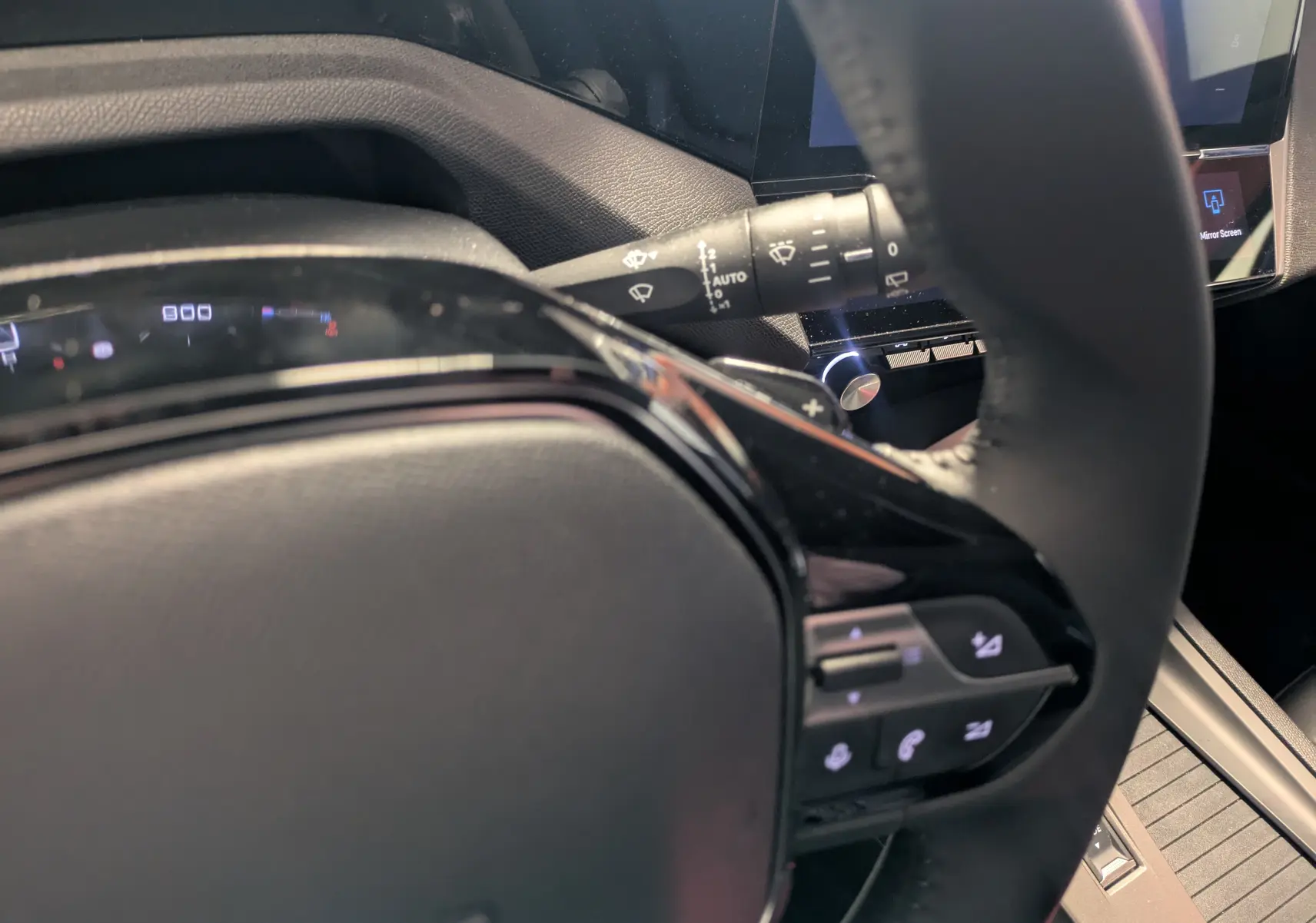 Vue rapprochée du volant noir de la Peugeot 308 2025 gris Artense, avec commandes intégrées visibles sur le côté droit.