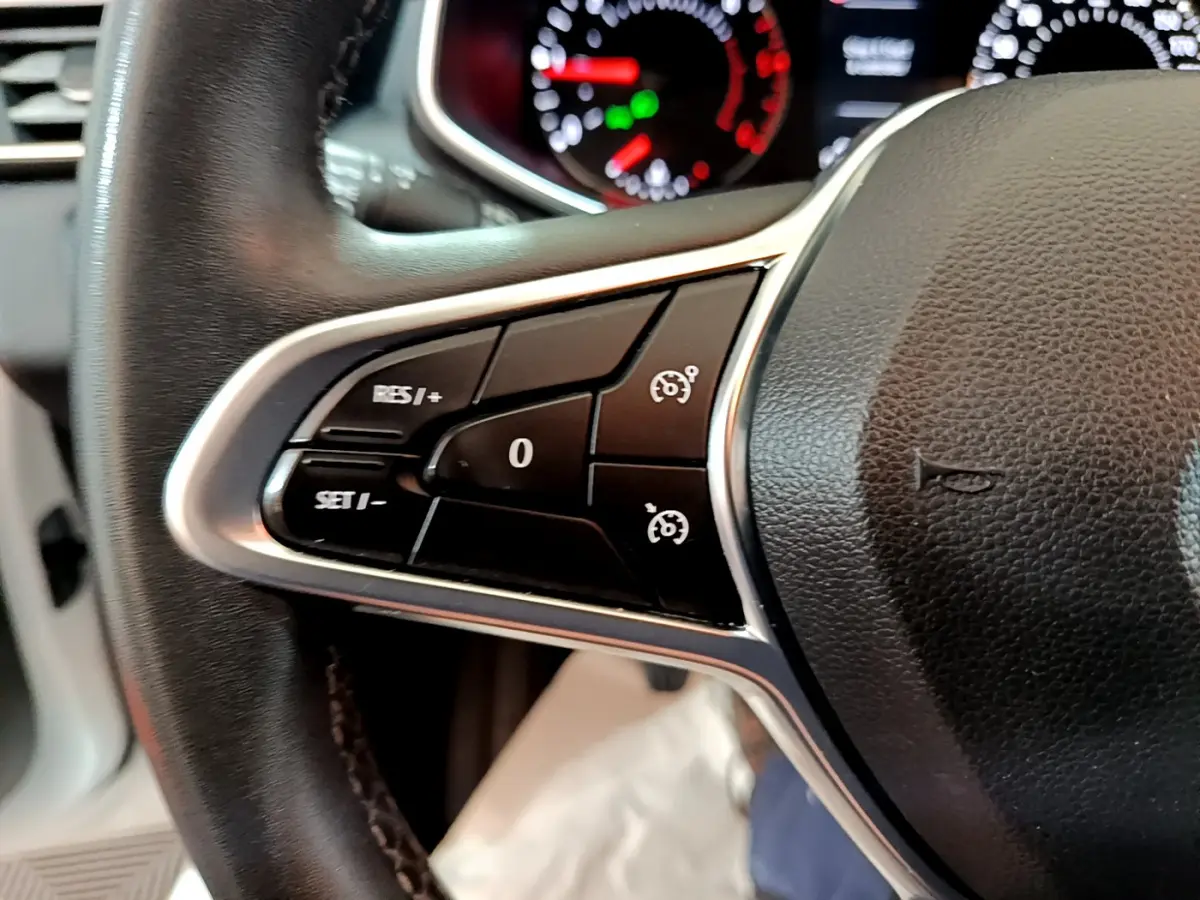 Gros plan sur les commandes du volant côté gauche d'une Renault Clio Business Blue dCi 85, tableau de bord en arrière-plan.