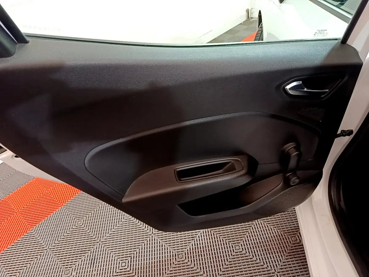 Gros plan sur la porte côté droit ouverte d'une Renault Clio Business Blue dCi 85 blanche, intérieur noir simple.