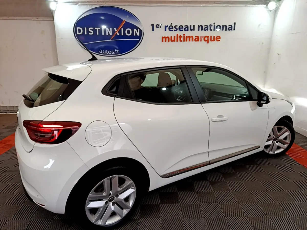 Vue côté droit arrière d'une Renault Clio Business Blue dCi 85 blanche avec jantes alliage et feux arrière LED allumés.