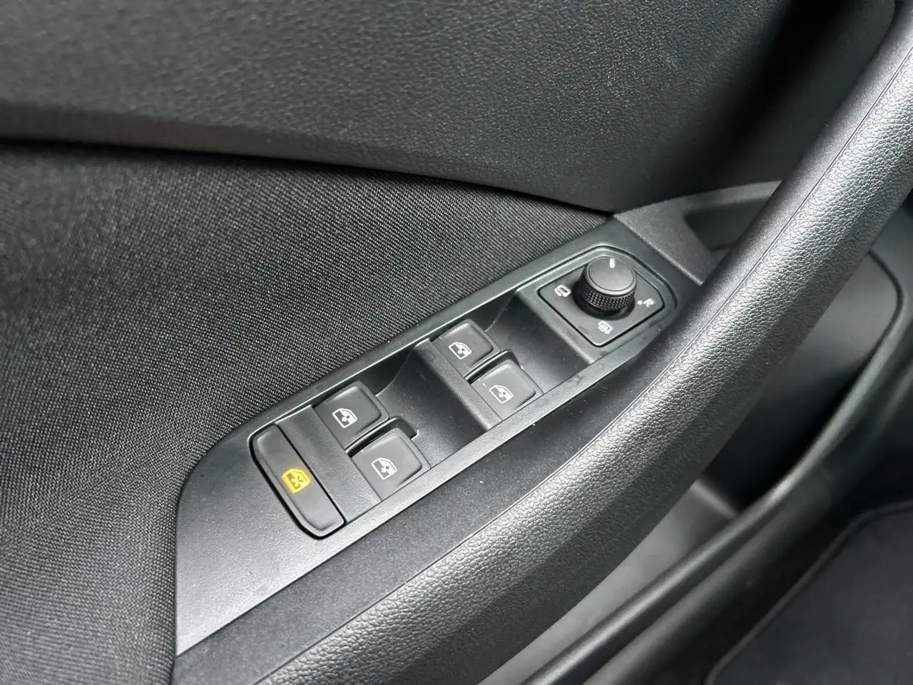 Gros plan sur les commandes de lève-vitres et rétroviseurs côté gauche intérieur d'une Skoda Kamiq gris graphite.