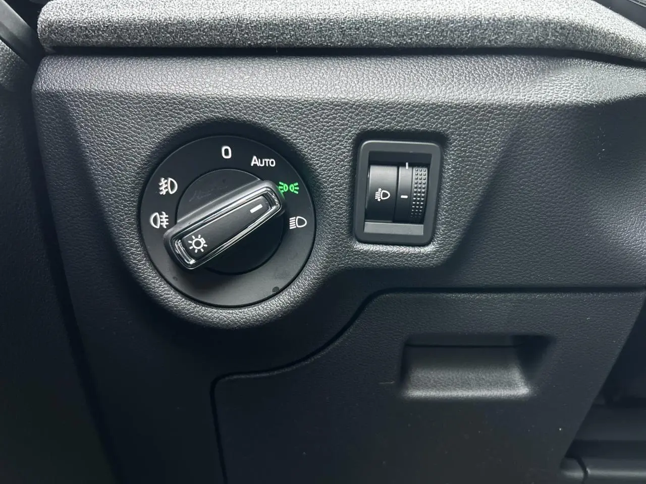 Gros plan sur le bouton de commande des phares du côté gauche intérieur du Skoda Kamiq gris graphite 2025.