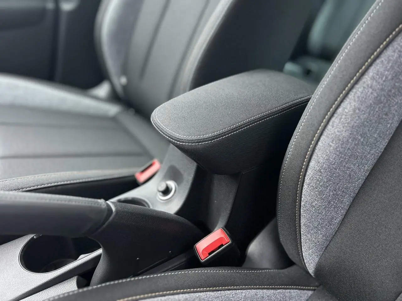 Détail de l'accoudoir central et des sièges avant gris foncé du Skoda Kamiq TSI 116 DSG7, intérieur moderne.
