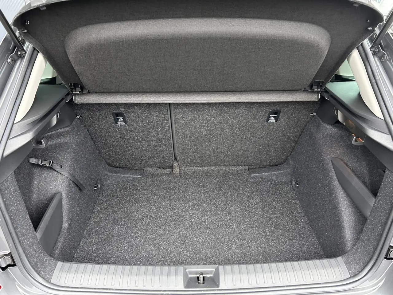 Coffre ouvert vu de l'arrière du Skoda Kamiq gris graphite, montrant un espace de chargement propre et spacieux.
