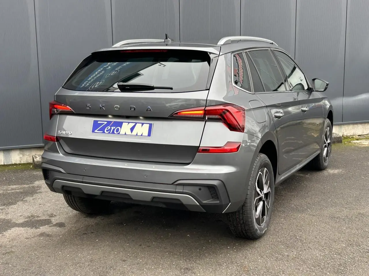 Vue 3/4 arrière droite d’un Skoda Kamiq gris graphite avec vitres surteintées et jantes alliage 16 pouces.