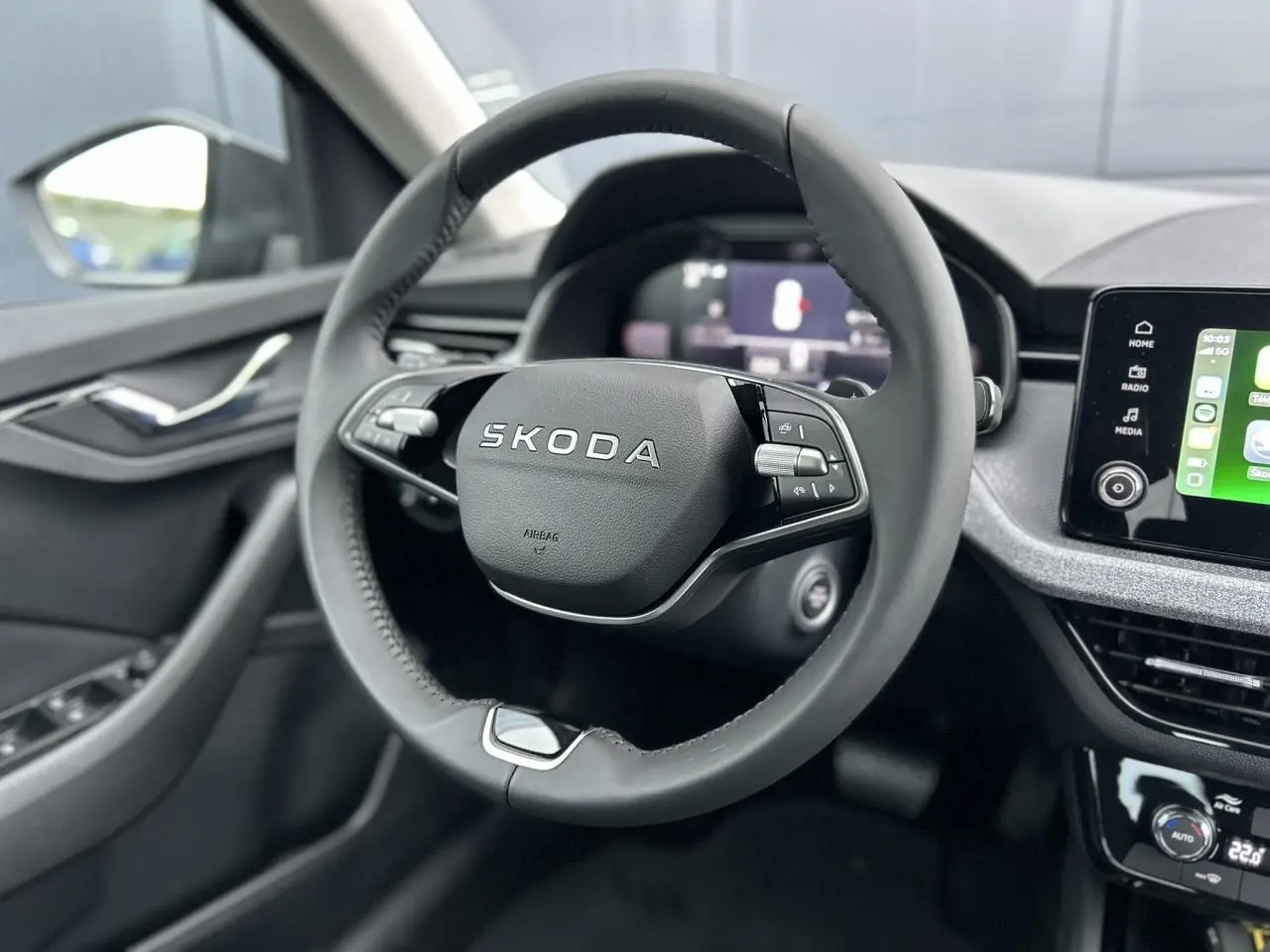 Vue intérieure centrée sur le volant noir multifonctions d’une Skoda Kamiq 2025 avec écran tactile et commandes au volant.