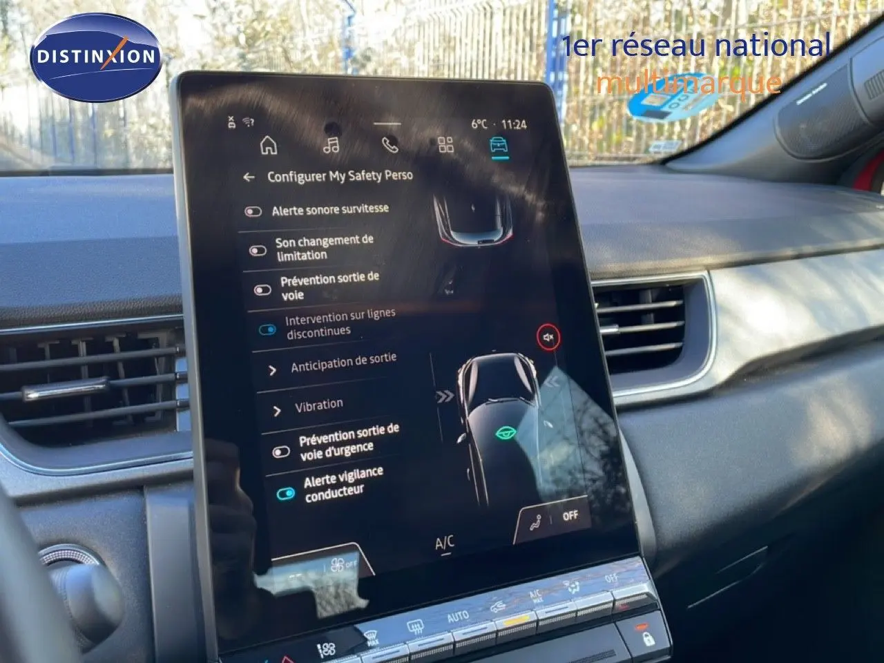 Vue intérieure centrée sur l'écran tactile du tableau de bord du Renault Captur rouge désir métal avec toit noir, affichant les aides à la conduite.