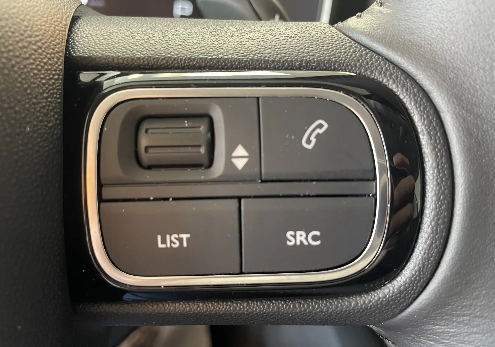 Gros plan sur les commandes au volant du Citroën C5 Aircross hybride gris platinium, boutons pour téléphone et liste audio.