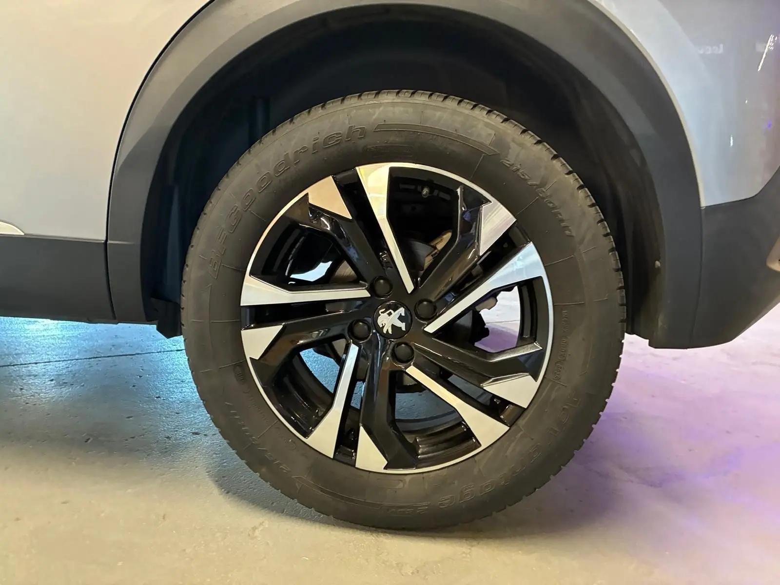 Gros plan sur la roue avant droite du Peugeot 2008 gris 2022, mettant en valeur la jante alliage noire et argentée.