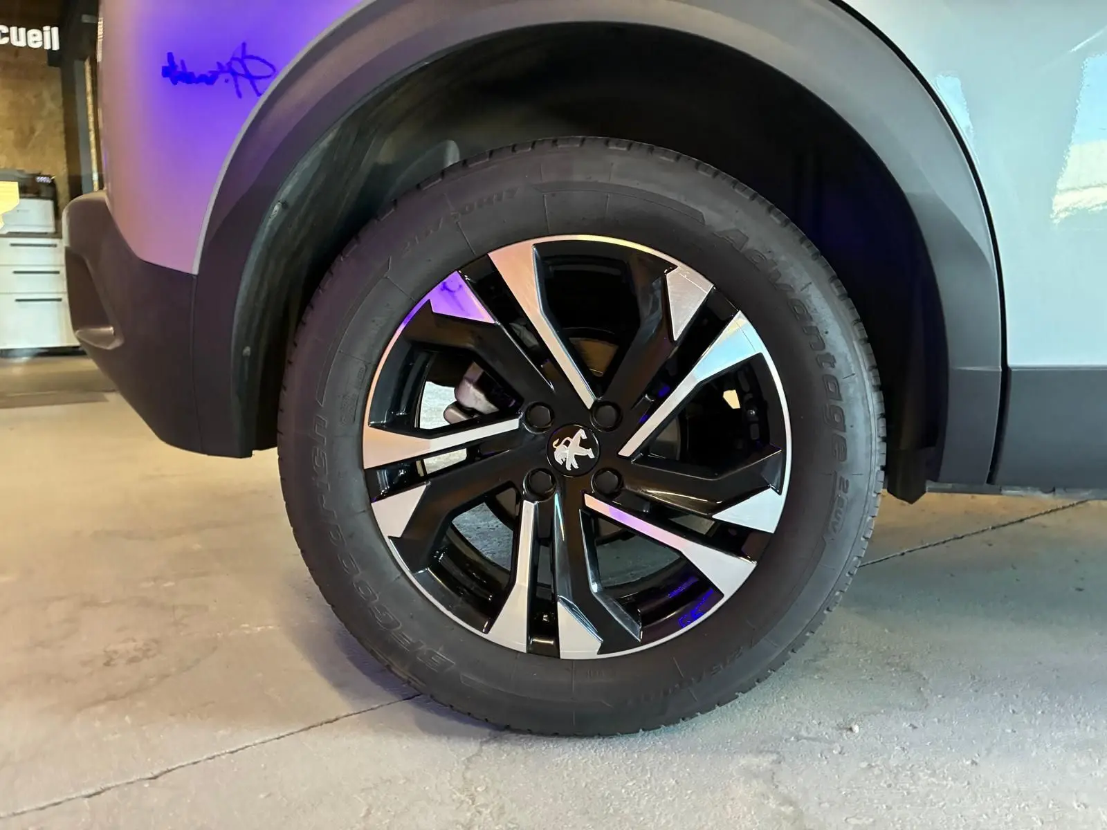 Gros plan sur la roue avant gauche du Peugeot 2008 gris 2022, mettant en valeur la jante alliage noire et argentée.