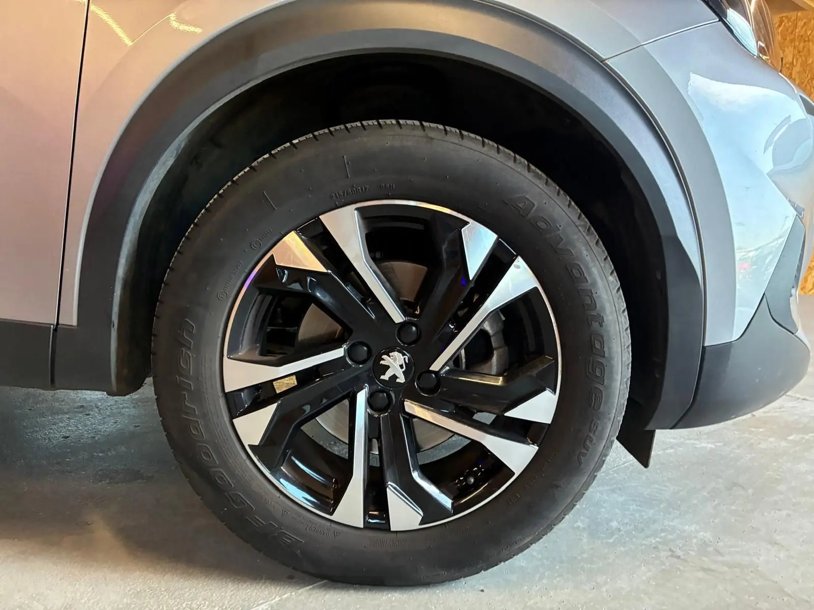 Gros plan sur la roue avant gauche du Peugeot 2008 gris 2022, mettant en valeur la jante alliage bicolore et le logo lion.