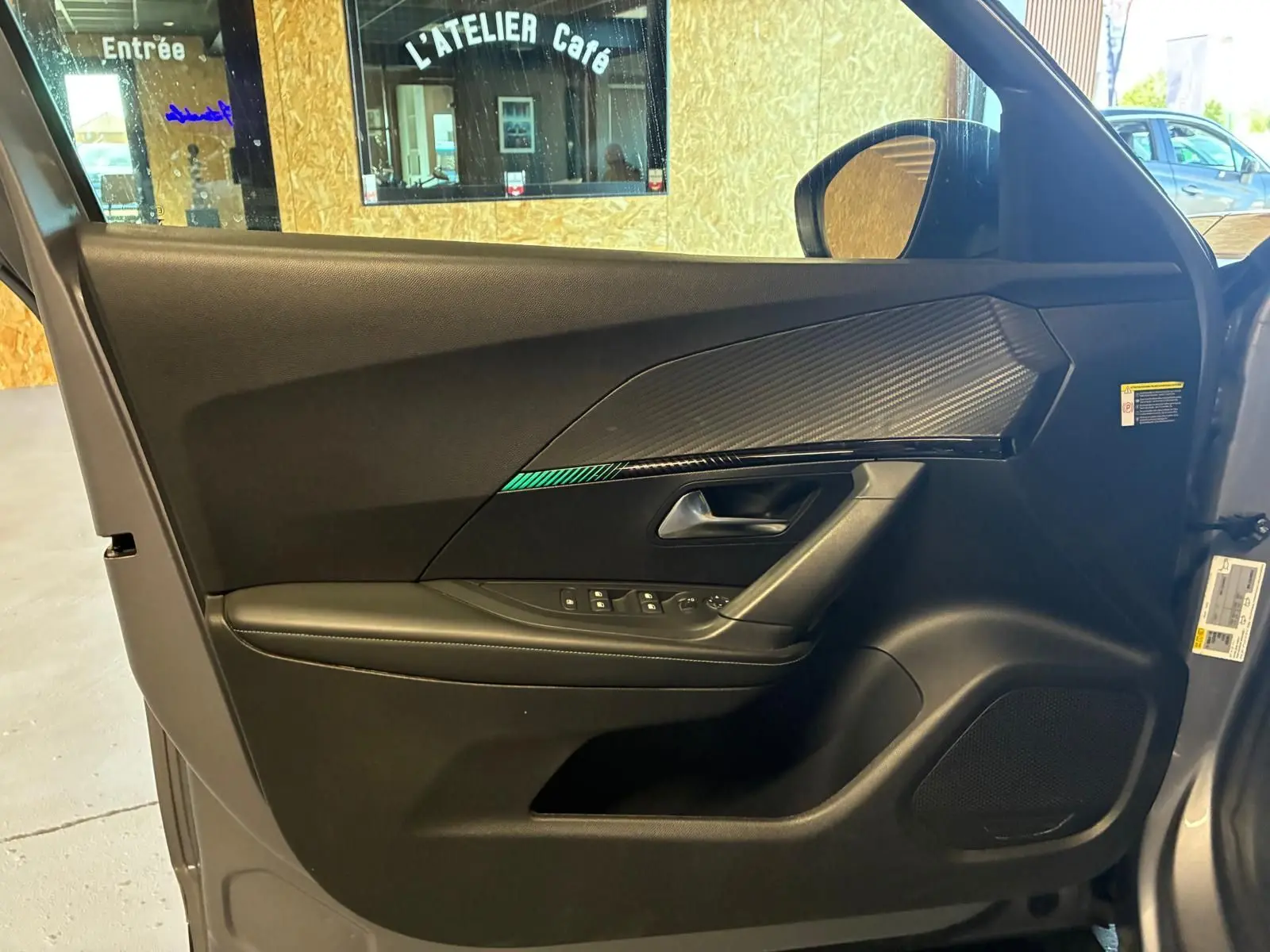Vue intérieure de la porte avant gauche du Peugeot 2008 gris, avec garniture noire et insert effet carbone.