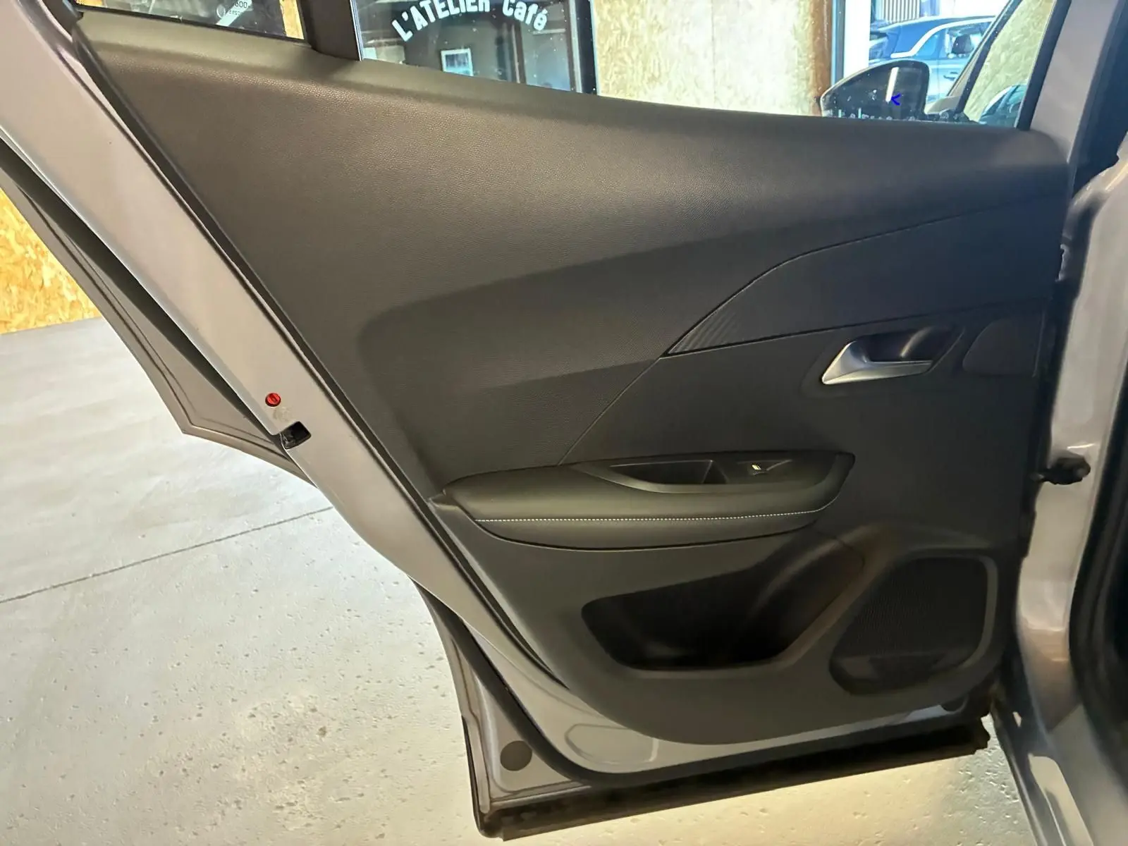 Vue intérieure de la porte arrière droite gris clair du Peugeot 2008 1.5 BlueHDi 2022 avec garniture noire et poignée argentée.