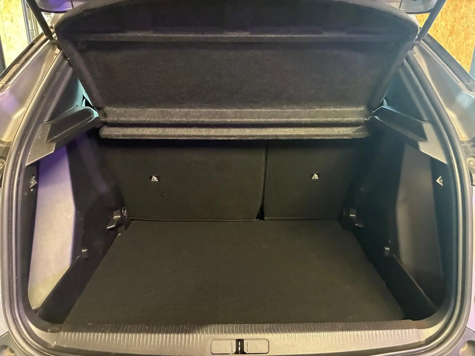 Coffre ouvert vu de l'arrière d'un Peugeot 2008 gris 2022, espace de chargement propre et vide.