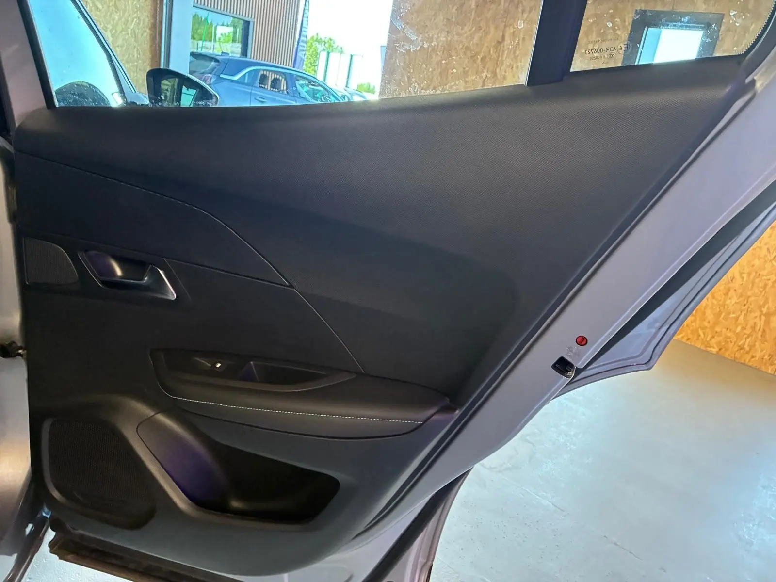 Vue intérieure de la porte arrière gauche noire du Peugeot 2008 gris 2022, mettant en valeur la poignée et les commandes.