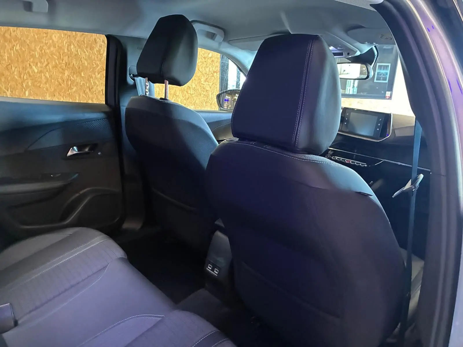 Vue intérieure arrière côté droit du Peugeot 2008 gris 2022, sièges noirs en tissu et tableau de bord avec écran tactile.