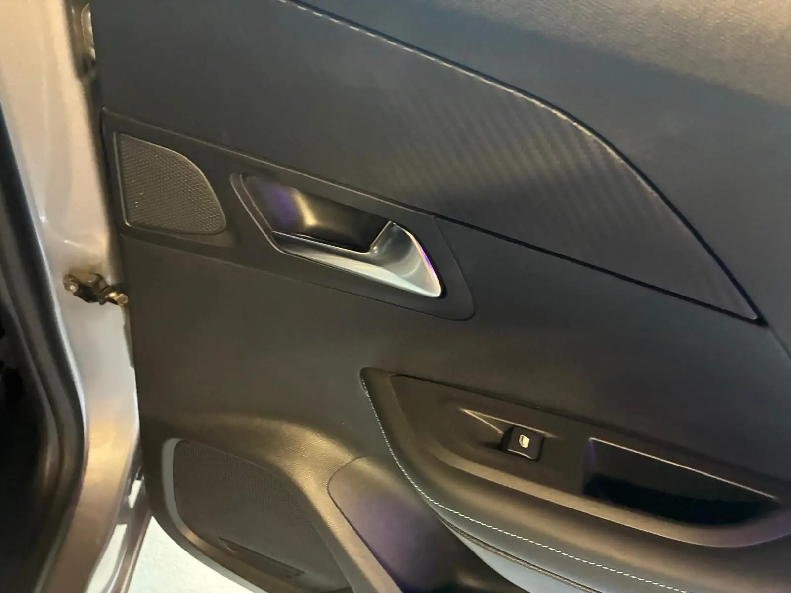 Vue rapprochée de la porte avant gauche gris clair du Peugeot 2008 avec poignée argentée et commande de fenêtre.