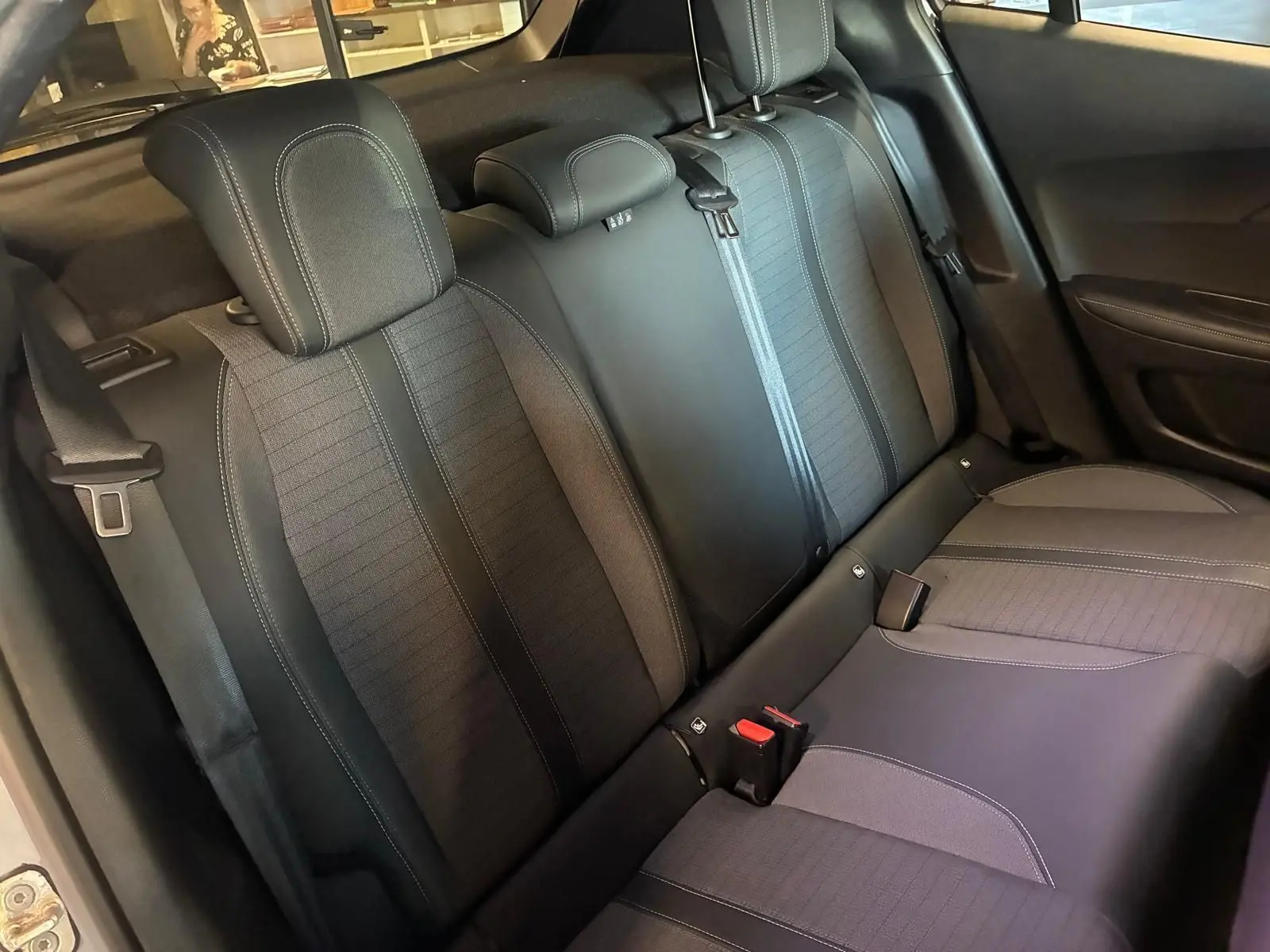 Vue intérieure sur les sièges arrière en tissu noir du Peugeot 2008 1.5 BlueHDi 130 gris, avec appuie-têtes et ceintures visibles.
