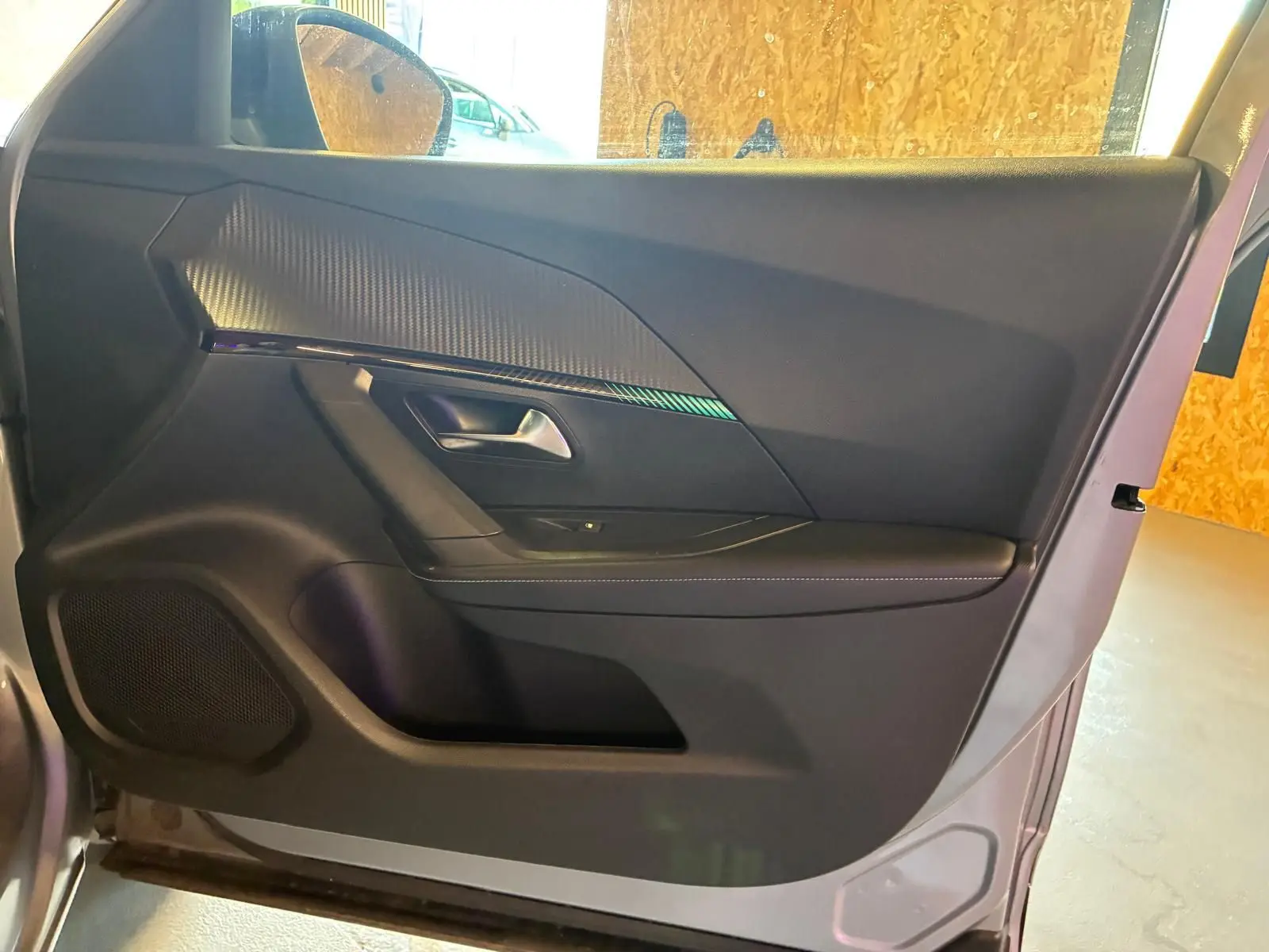 Vue intérieure de la porte avant gauche d’un Peugeot 2008 gris, avec habillage noir et insert décoratif texturé.