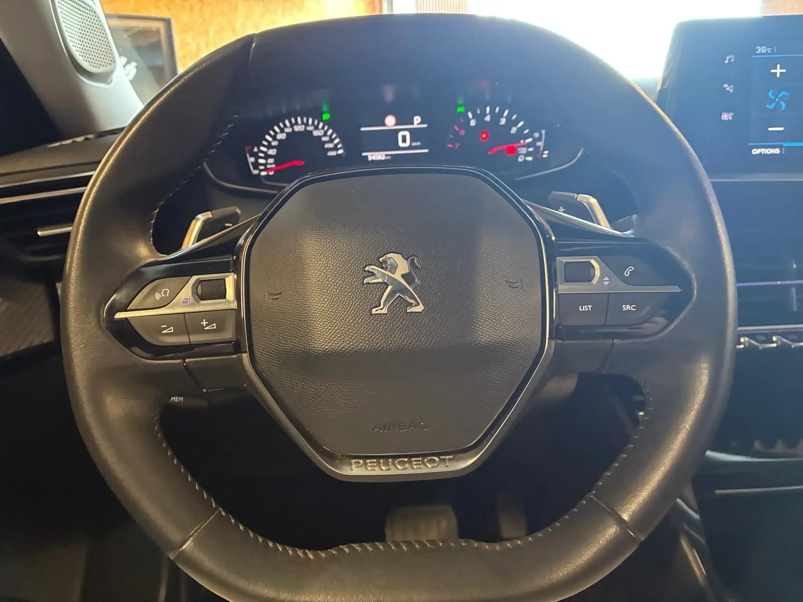 Vue rapprochée du volant noir du Peugeot 2008 1.5 BlueHDi 130 avec commandes intégrées et tableau de bord numérique.